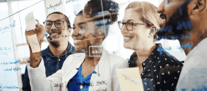 Een team brainstormt samen, schrijft ideeën op een glazen bord en werkt enthousiast samen.