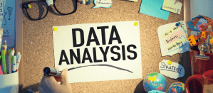 Kurkbord met "Data Analysis" op papier en strategienotities, omringd door kantoorbenodigdheden.