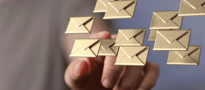 Hand wijst naar zwevende gouden enveloppen op een wazige achtergrond, digitale communicatie.