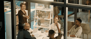 Mensen in een moderne vergaderruimte met glazen wanden, bezig met een teamoverleg