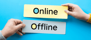 Twee handen houden borden met de woorden "Online" en "Offline" vast tegen een blauwe achtergrond.