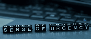 Zwarte blokletters spellen de woorden "Sense of Urgency" op een toetsenbordachtergrond.