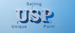 Houten letters USP op blauwe achtergrond met woorden Unique Selling Point.