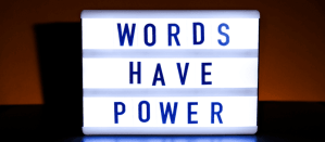 Verlichte lightbox met de tekst "Words Have Power" in blauwe letters tegen een donkere achtergrond.