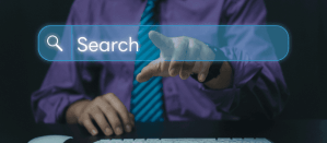 Man in paarse blouse en stropdas wijst naar een digitale zoekbalk met de tekst "Search" boven een toetsenbord.