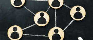 Houten schijven met gebruikersiconen verbonden door lijnen op een schoolbord, concept van netwerkorganisatie.