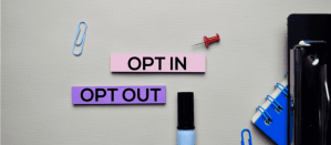 Twee gekleurde labels met de teksten "OPT IN" en "OPT OUT" op een bureau met kantoorartikelen.