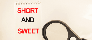 Notitieboek met de tekst "SHORT AND SWEET" en een vergrootglas ernaast.