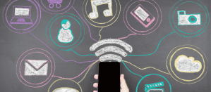 Hand met smartphone verbonden met social media pictogrammen op krijtbord.