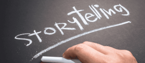 Hand schrijft het woord "Storytelling" met wit krijt op een zwart bord.