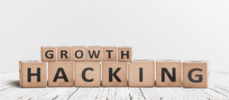 Houten blokken met de woorden 'Growth Hacking' op witte houten vloer, focus op slimme groei