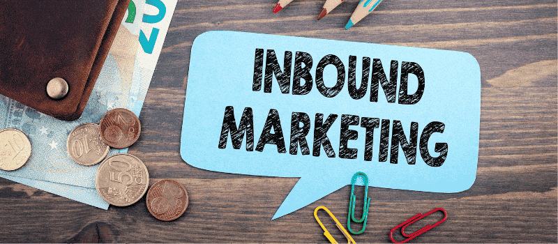 Blauwe tekstballon met &amp;apos;Inbound Marketing&amp;apos; op houten tafel naast eurogeld en paperclips