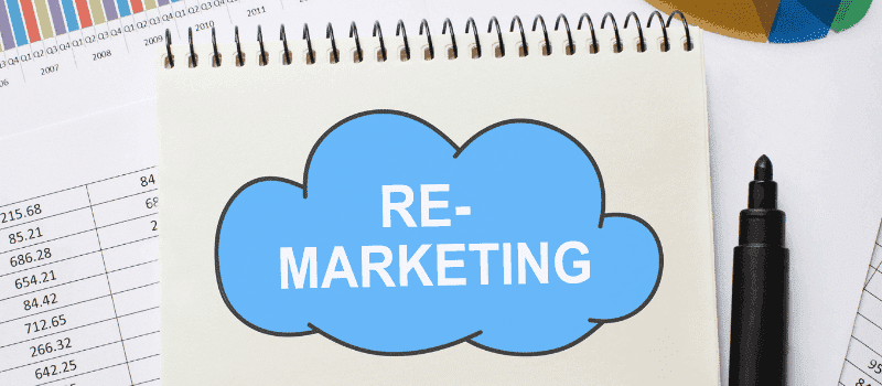 Notitieboek met blauwe wolk en tekst 'REMARKETING', omringd door grafieken en stift